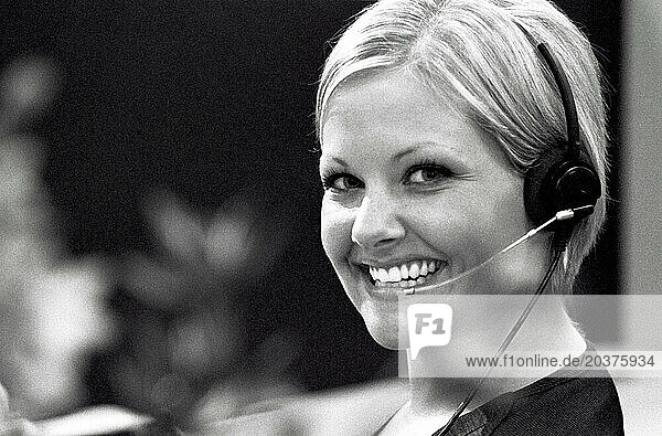 A young woman smiles at her office desk.