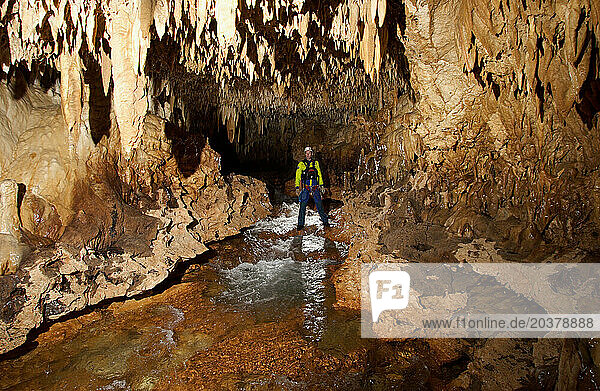 A cave explorer adds scale to a stream passage in a cave in New Britain