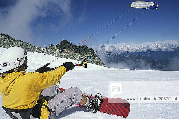 A kiteboarder carves throug the snow.