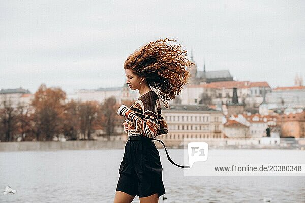 Curly redhead young woman in Prague  cloudy