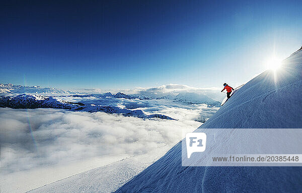 Austria  Salzburger Land  Female skier sliding down slope high above fog shrouded valley