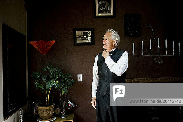 A man wearing a tuxedo adjusts his tie while looking in a mirror in Coeur d'Alene, Idaho.