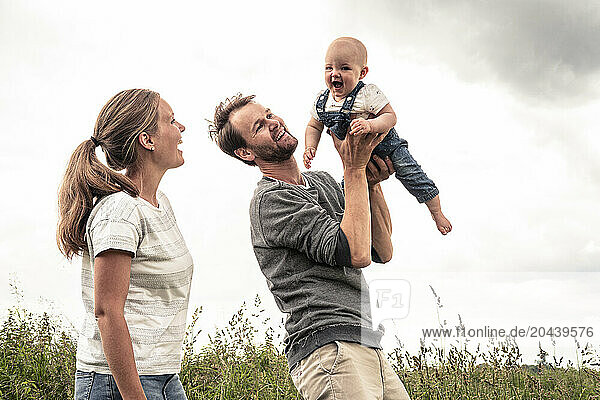 Playful family playing with daughter in meadow