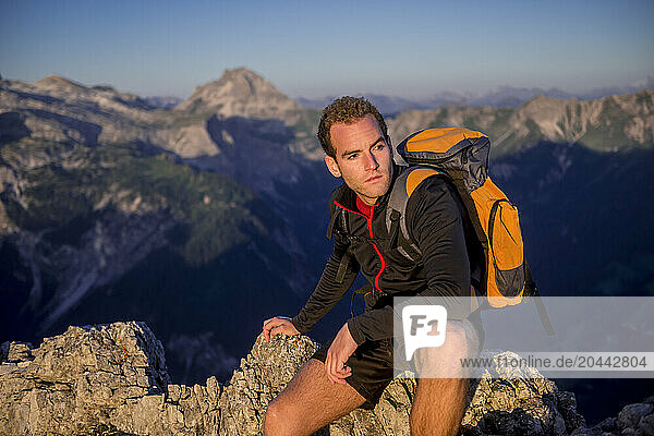 Young man sitting on Steinfeldspitze rock under sky at sunrise in Altenmarkt  Zauchensee  Salzburg  Austria