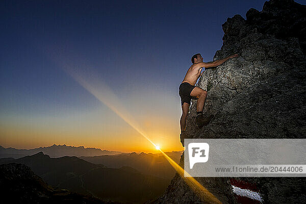 Hiker climbing Steinfeldspitze rock at sunrise in Altenmarkt  Zauchensee  Salzburg  Austria