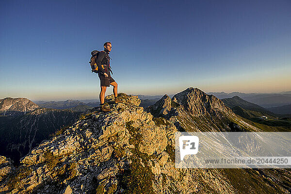 Man standing on Steinfeldspitze rock at sunrise in Altenmarkt  Zauchensee  Salzburg  Austria