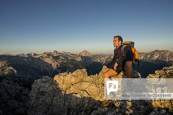 Man sitting on Steinfeldspitze rock at sunrise in Altenmarkt  Zauchensee  Salzburg  Austria