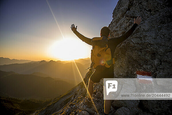 Carefree man standing on Steinfeldspitze rock under sky at sunrise in Altenmarkt  Zauchensee  Salzburg  Austria