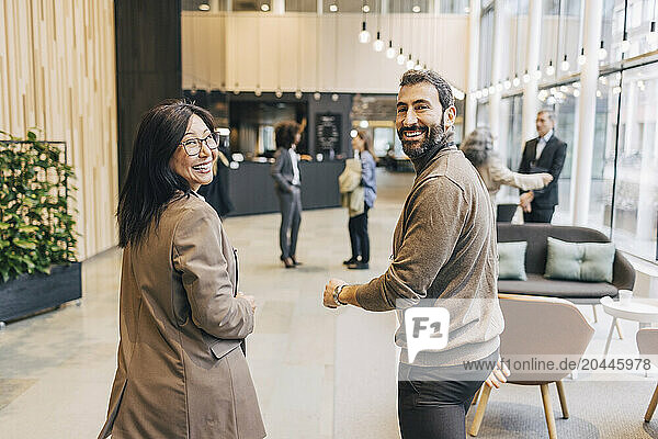 Portrait of happy male and female delegates walking in lobby at convention center