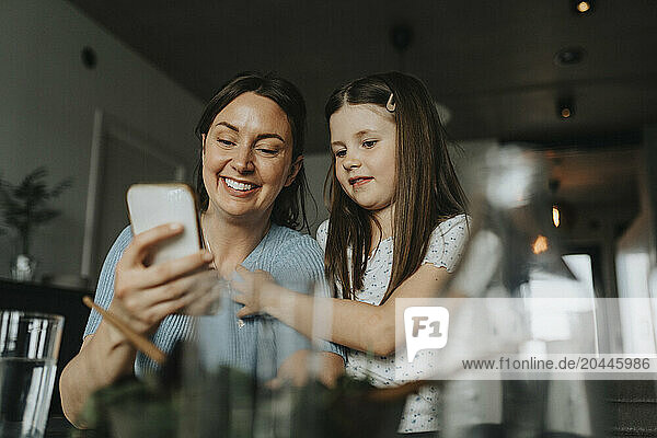 Mother and daughter using smart phone at home