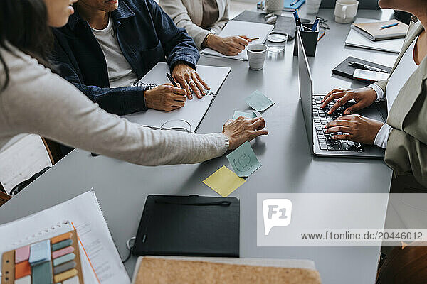 High angle view of businesswoman sticking adhesive notes on desk at office