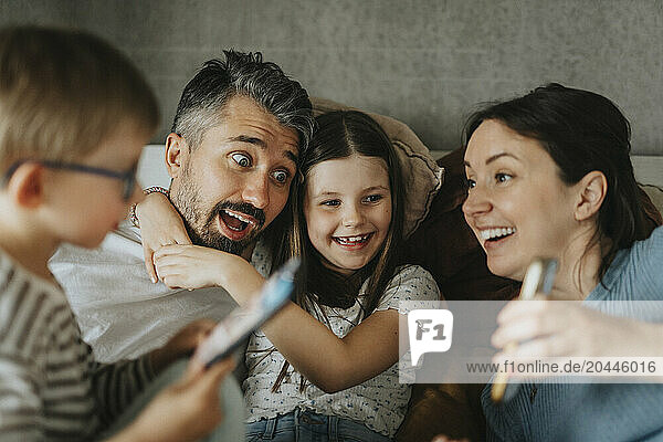 Playful family spending leisure time with smart phones at home