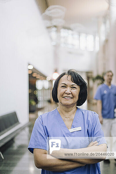 Portrait of smiling female doctor with arms crossed in hospital lobby