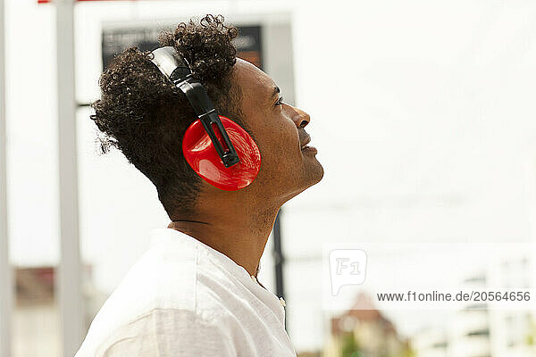 Smiling man wearing wireless headphones and listening to music