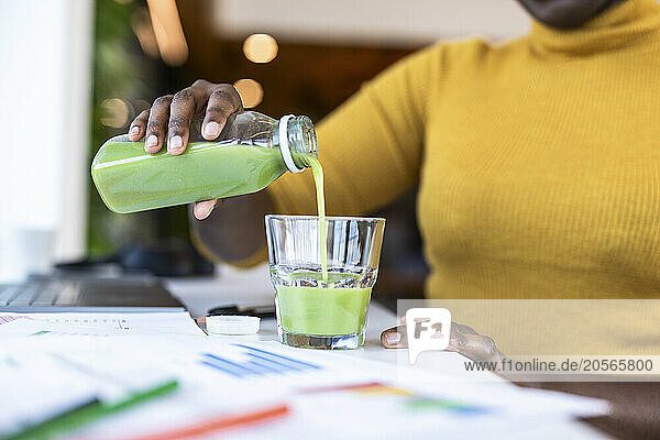 Hands of businesswoman pouring juice in glass