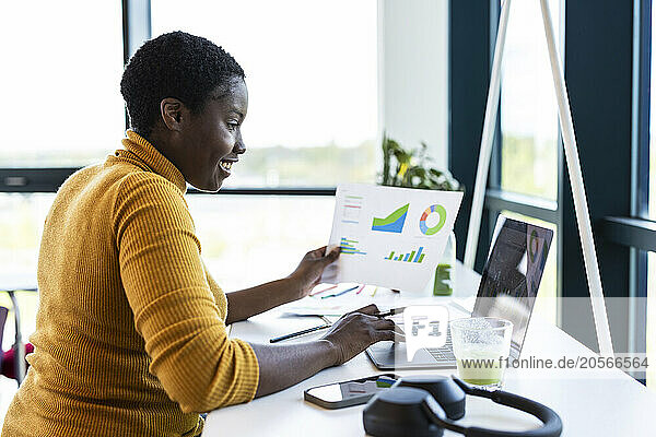Happy businesswoman working on laptop and sitting in coworking office