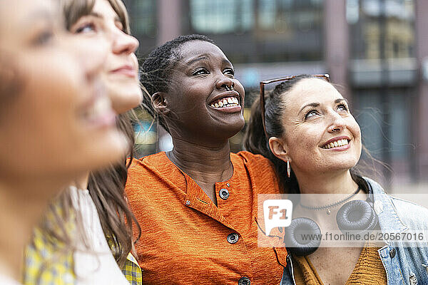 Happy multiracial female friends looking up