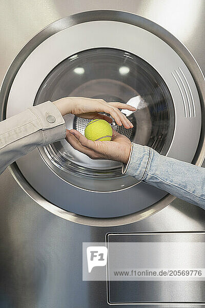 Hands of couple holding tennis ball in laundromat