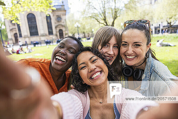 Happy woman taking selfie with multiracial female friends at park