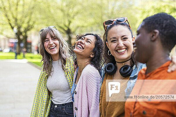Cheerful multiracial female friends standing with arms around