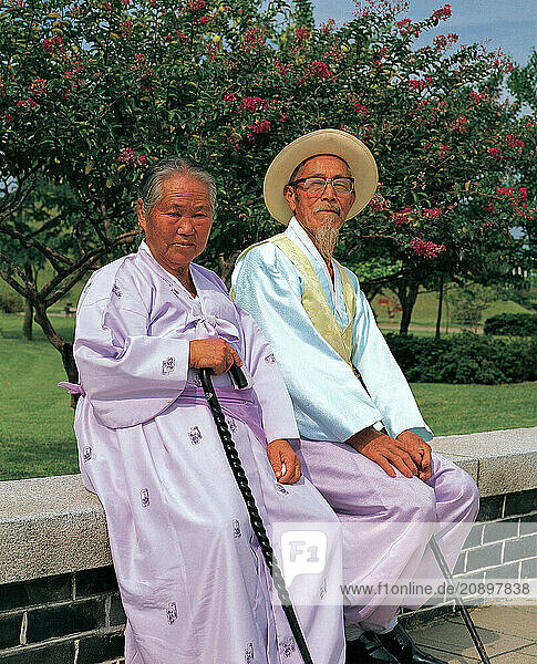 South Korea. Seoul. Old couple sitting on low wall.