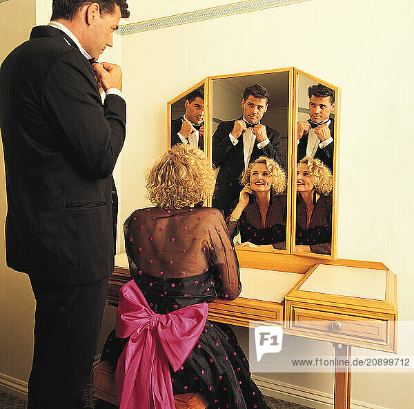 Young couple in hotel room. Dressing for dinner.