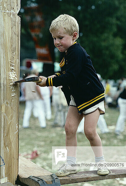 Australia. Children. Boy practicing wood chopping sport.