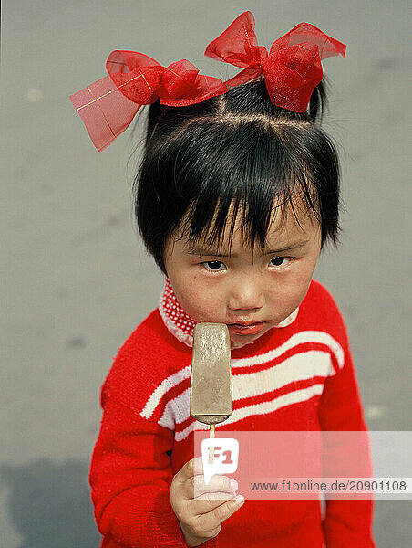 China. Shanghai. Outdoor portrait of little girl child with ice-cream.