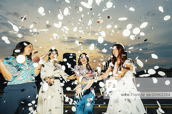 Cheerful friends celebrating together and having fun with confetti