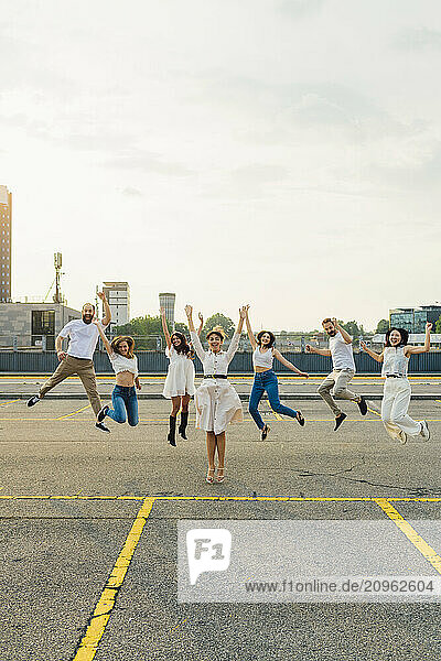Cheerful friends jumping together and having fun on road