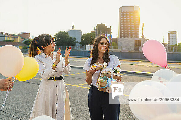 Happy woman applauding and celebrating friends birthday on road at sunset