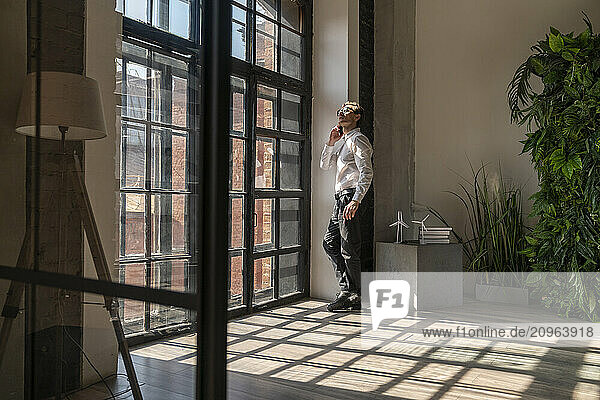 Businessman talking on smart phone by window