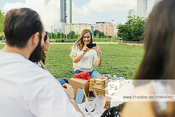 Happy woman photographing friends with smart phone