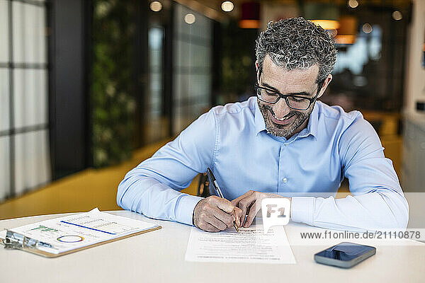 Businessman signing contract paper at co working space