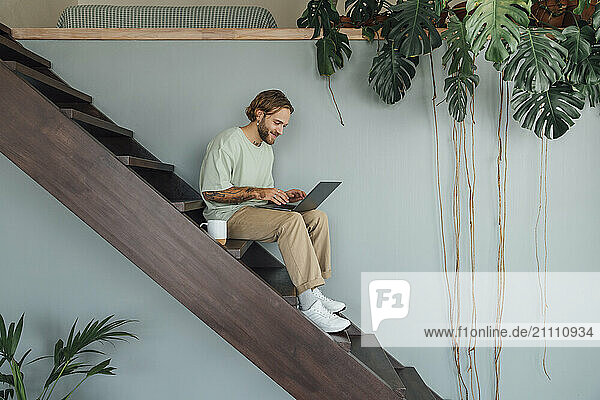 Smiling businessman working on laptop at home