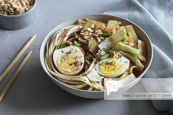 White cabbage soup with miso and udon noodles and boiled eggs and peanuts as topping