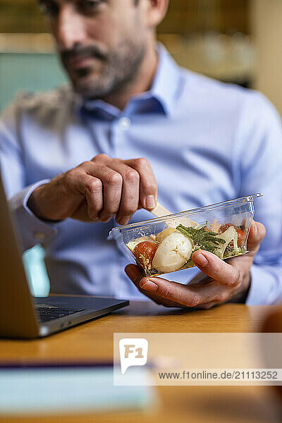 Businessman holding lunch box at co working space