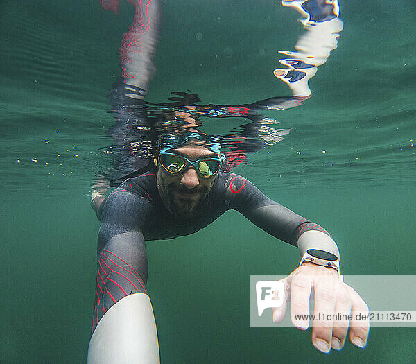 Tourist in wetsuit taking selfie and swimming underwater