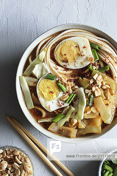 White cabbage soup with miso and udon noodles and boiled eggs and peanuts as topping