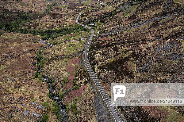Aerial view of the Glencoe Valley and its winding road with scenic mountain sides in Scotland.