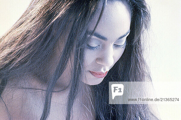 Close up portrait of beautiful  dark-haired woman looking down.