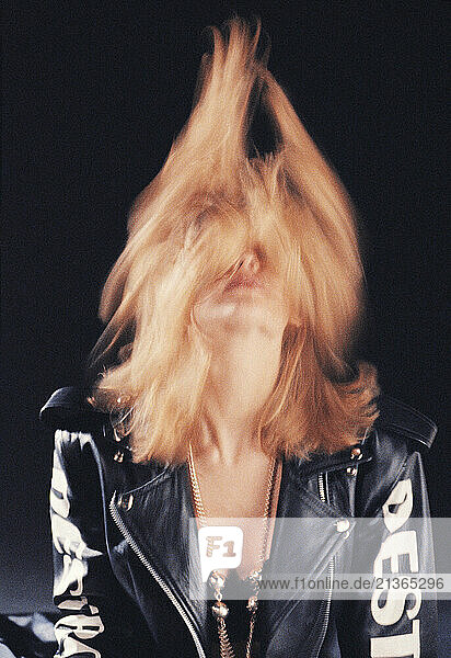 Studio portrait of young blond hair woman wearing black leather jacket.