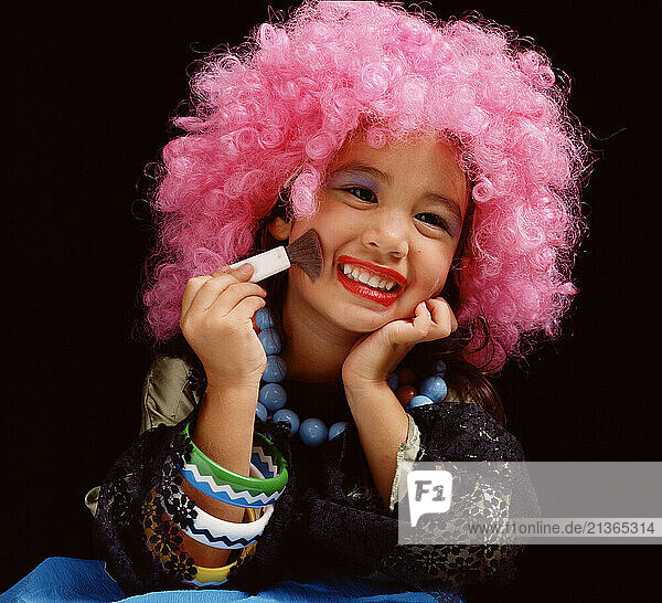 Lifestyle. Children. Little girl with pink wig playing with makeup.