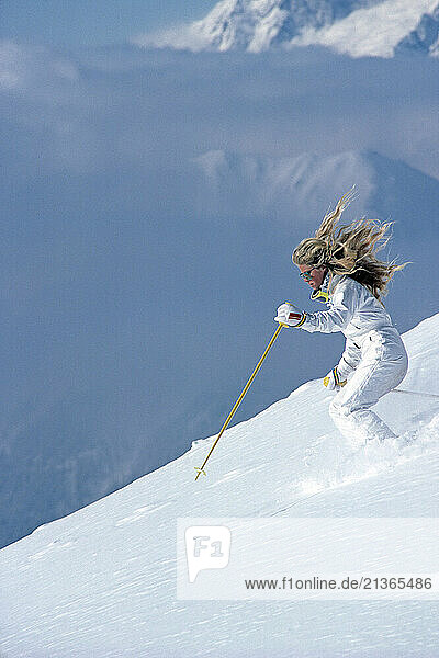 New Zealand. Young woman downhill skiing on alpine slopes.