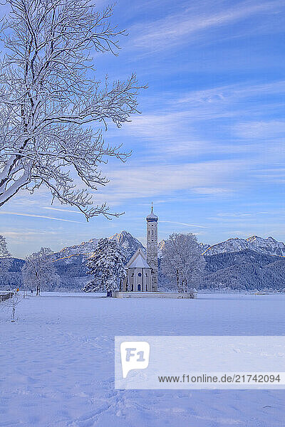 Blick auf Sankt Coloman in Schwangau im Winter mit Schnee  im Hintergrund die Allgäuer Alpen