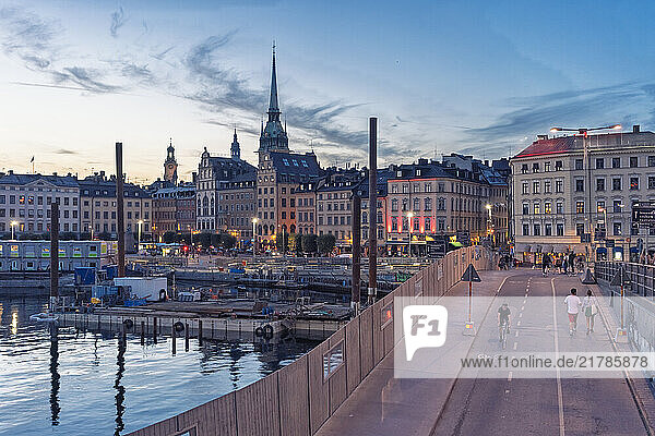 Sunset view over Stockholm bustling city waterfront with pedestrians and historic architecture of Gamlastan old city with the german church spire  Stockholm  Sweden