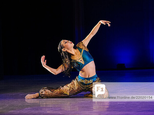 Dancer elegantly poses on stage with vibrant blue and gold costume under dramatic lighting  The Nutcracker  Bainbridge Island  USA