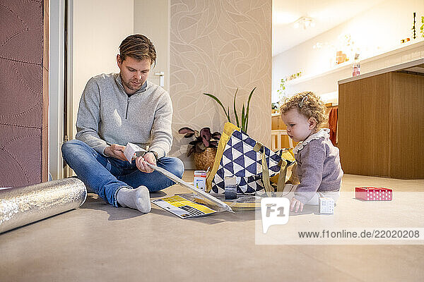 Man and toddler engaged in a home DIY project  sitting on a living room floor. Netherlands