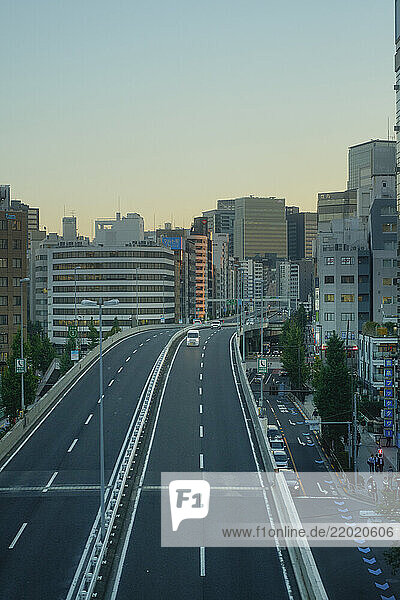 Elevated highway leading into a cityscape with tall buildings at dusk. Tokyo  Japan