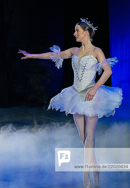 Ballet dancer in white tutu performs gracefully on a misty stage with blue lighting. The Nutcracker  Bainbridge Island  USA